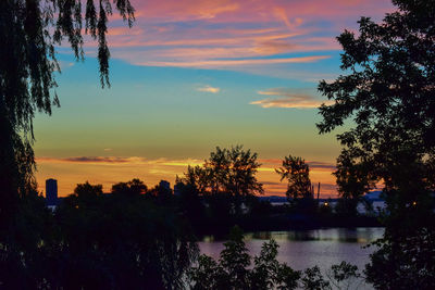 Silhouette trees by lake against sky during sunset