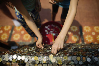 Overhead view of sisters sticking coins on rock at temple
