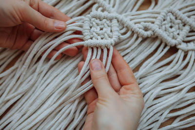 Close-up of the hand of a girl who weaves macrame technique