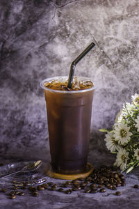 Thai coffee in a tall plastic cup there is steam next to the glass, cold.