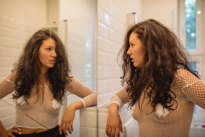 Angry woman looking at her reflection in mirror at home