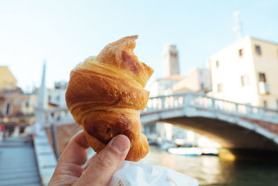 Cropped hand holding croissant