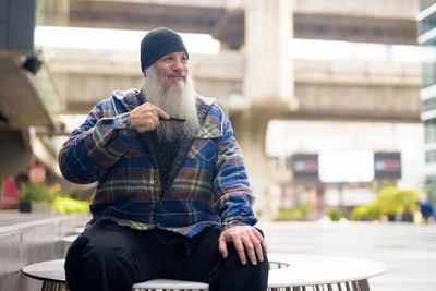 Man looking away while sitting outdoors