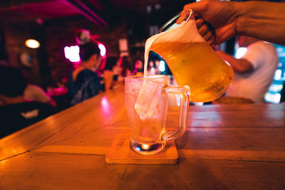 Cropped hand of bartender pouring beer in glass on counter