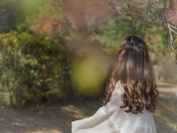 Rear view of woman standing against trees