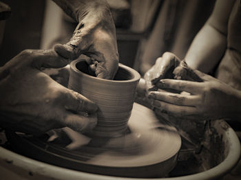 Cropped hands making pottery at workshop