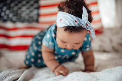 Girl crawling on bed against american flag