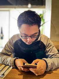 Young man using mobile phone while sitting on table