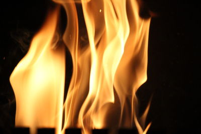 Close-up of burning candle against black background