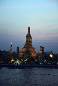 Illuminated wat arun by river against sky