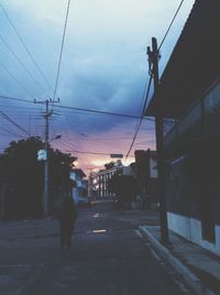 Man walking on road against sky during sunset