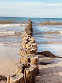 Wooden posts on beach against sky