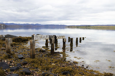 Wooden posts on beach against sky