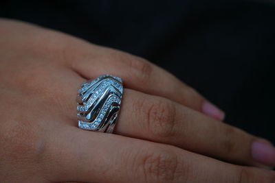 Close-up of woman showing ring against black background