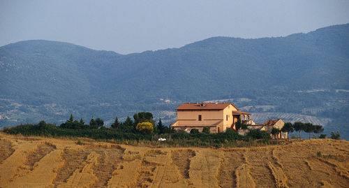 Scenic view of agricultural field by mountains against sky