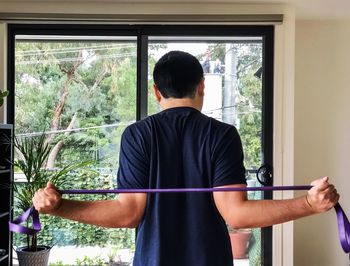 Rear view of man doing resistance band exercises.