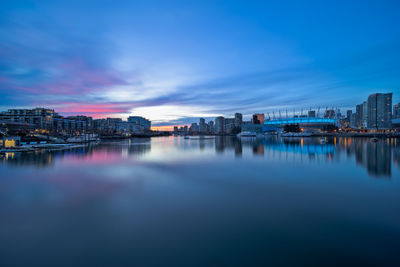 Scenic view of river and buildings against blue sky