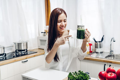 View of young woman holding jar in kitchen