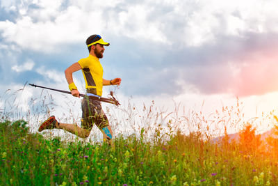 Man runner with rackets in hand down in the meadows in the summer