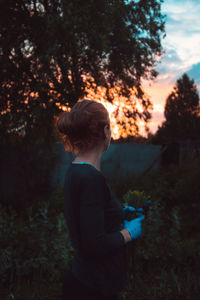 Rear view of child standing on land during sunset