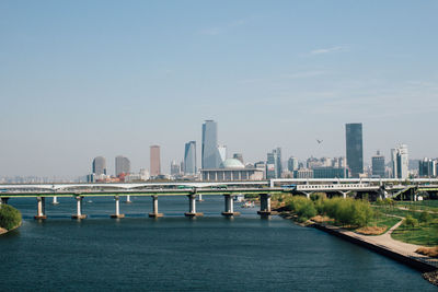 Bridge over river in city against clear sky