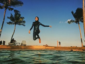 Man jumping in swimming pool against sky