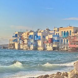 Buildings by sea against sky