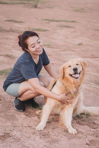Smiling young woman playing with dog on field