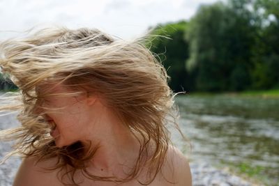 Playful young woman tousling hair outdoors