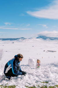 Rear view of man sitting on snow