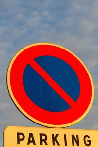 Close-up of no parking sign against sky