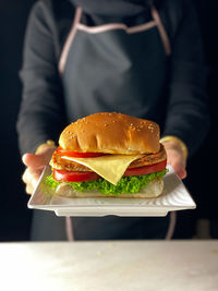 A levitation phoyo of a chef handhokding a chicken burger in dark mood photography 