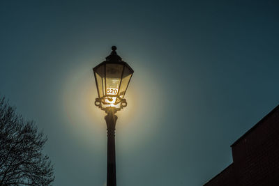 Low angle view of illuminated street light against blue sky