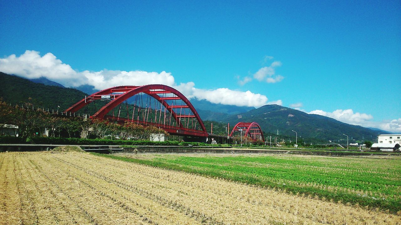 sky, cloud - sky, mountain, grass, built structure, architecture, blue, landscape, cloud, field, tree, transportation, nature, outdoors, day, tranquility, plant, no people, tranquil scene, beauty in nature