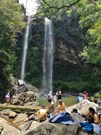 Group of people on rocks against waterfall