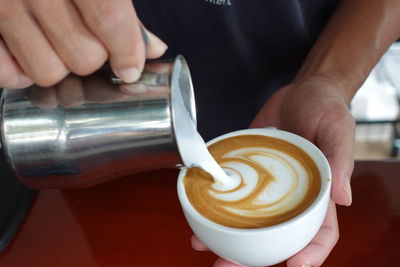 Cropped hand holding coffee on table