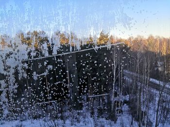 Snow covered landscape seen through wet window