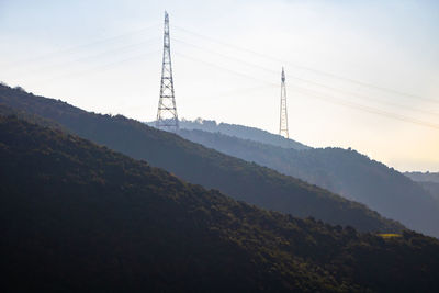 Electricity pylon on mountain against sky