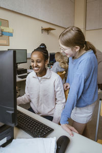 Happy multiracial girls having fun in computer class at school