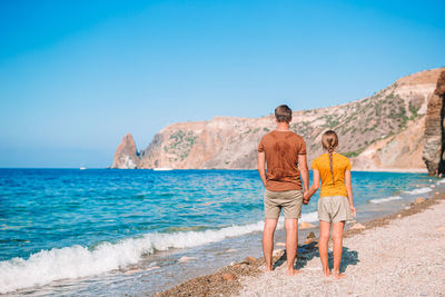 People on beach by sea against clear sky