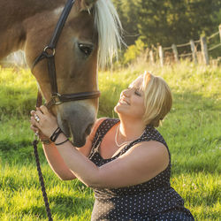 Portrait of young woman with horse standing on field