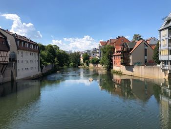 Buildings by river against sky