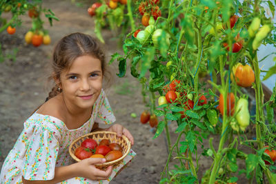 Portrait of smiling girl holding tomatoes in basket