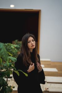 Portrait of beautiful young woman standing against wall