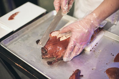 Close-up of chef's hand preparing and cutting peking duck