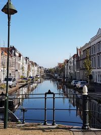 Reflection of buildings in water against clear blue sky