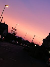 Cars on road against sky at sunset