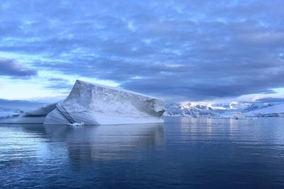 Scenic view of glaciers in sea against sky