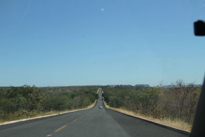 Road amidst trees against clear sky