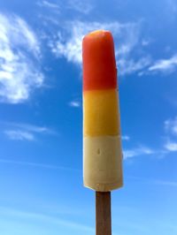 Low angle view of orange pole against blue sky
